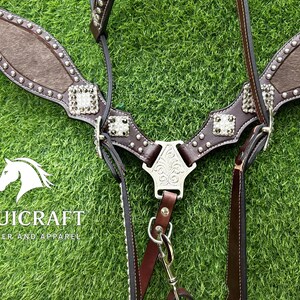 Puede incluir: Un juego de guarnicioner&iacute;a de cuero marr&oacute;n para caballos con adornos plateados. El juego incluye un petral, una brida y riendas. El petral presenta un panel central de material marr&oacute;n texturizado y tachuelas plateadas decorativas.