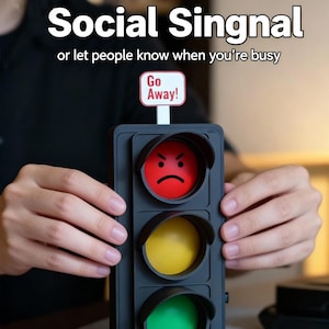 Könnte beinhalten: Ein schwarzes Social-Signal-Gerät mit drei Lichtern: rot mit einem grimmigen Gesicht, gelb und grün. Das Gerät trägt den Text "Social Singnal" und "or let people know when you're busy". Ein kleines Schild zeigt "Go Away!"