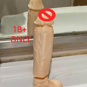 May include: A beige-colored adult novelty item with a realistic design. The item is standing upright on a white surface. The text "18+ ONLY" is visible in the image.