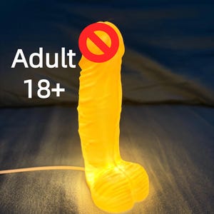 Puede incluir: Un juguete para adultos de color amarillo con una superficie texturizada, iluminado desde dentro. El texto "Adult 18+" es visible en blanco. El artículo está sobre un fondo oscuro.
