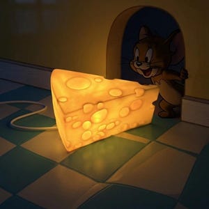 May include: A glowing cheese-shaped lamp with a cartoon mouse peeking out from a mouse hole. The lamp is yellow with several round holes, and the mouse is brown and white. The lamp sits on a checkered floor.