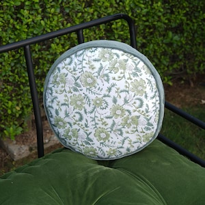 May include: A circular cushion featuring a floral design in green and white, set on a green velvet cushion. The cushion has a green velvet trim and is on a black metal frame, suitable for outdoor use. The cushion's diameter is approximately 30 cm.