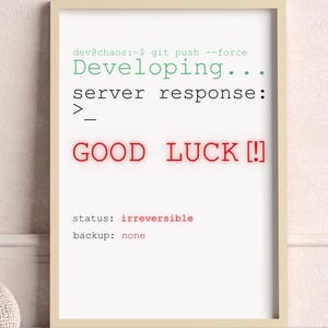 Op de afbeelding: Een ingelijste print met de tekst "GOOD LUCK [!]" in het rood en andere code-regels in het groen. De print staat in een lichtgekleurde lijst, leunend tegen een muur. Een witte kruk met een gebreide deken en een gebreide poef staan op de voorgrond.