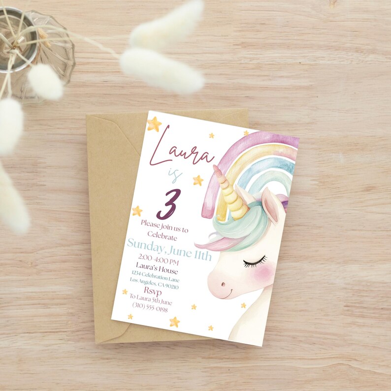 May include: A birthday invitation featuring a watercolour unicorn with a rainbow and stars. The invitation reads "Laura is 3" with event details. The invitation is on a white background with a brown envelope.
