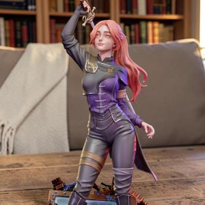 Könnte beinhalten: Detaillierte Figur einer Kriegerin in dynamischer Pose, die ein Schwert hochhält. Die Figur trägt ein dunkelviolettes und graues Outfit mit komplizierten Details, darunter ein dekoratives Emblem. Ihr langes, rotes Haar fließt, und die Basis hat metallische Akzente.