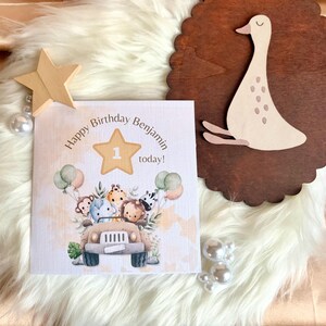 以下が含まれることがあります： 「Happy Birthday Benjamin today!」のテキストが入ったバースデーカードには、漫画の動物と風船がいっぱいのサファリジープが描かれています。木製の星と装飾的な木製のカモも存在します。