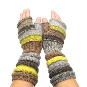May include: A pair of fingerless gloves with a striped pattern in shades of brown, gray, and yellow. The gloves are knit and have a long cuff.