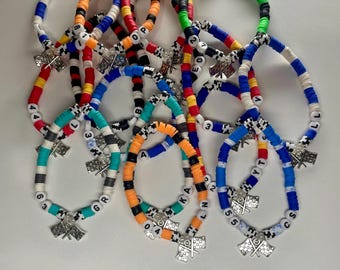 May include: A collection of colorful bracelets with the text "F1 Driver Bracelets". Each bracelet features a mix of colored beads, letter beads, and a silver charm with a checkered flag design. The bracelets are in various colors including blue, orange, and green.