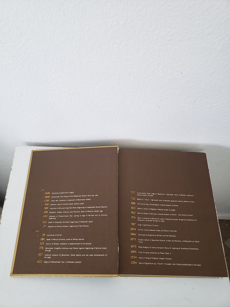 May include: A brown book with a timeline of historical events. The book has a gold spine and gold lettering. The timeline includes dates and descriptions of events from 2600 BC to 1204 AD.