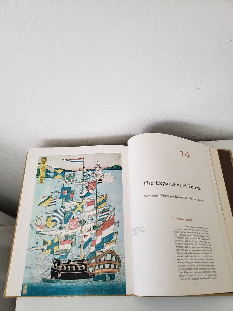 May include: A colorful illustration of a ship with many flags from different countries. The ship is sailing on a body of water with a mountain range in the background. The text "The Expansion of Europe" is printed in black on a white background.
