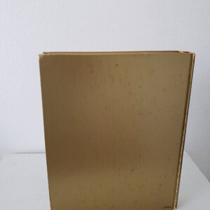 May include: A gold-colored book with a plain cover and the number 38860 printed on the bottom right corner.
