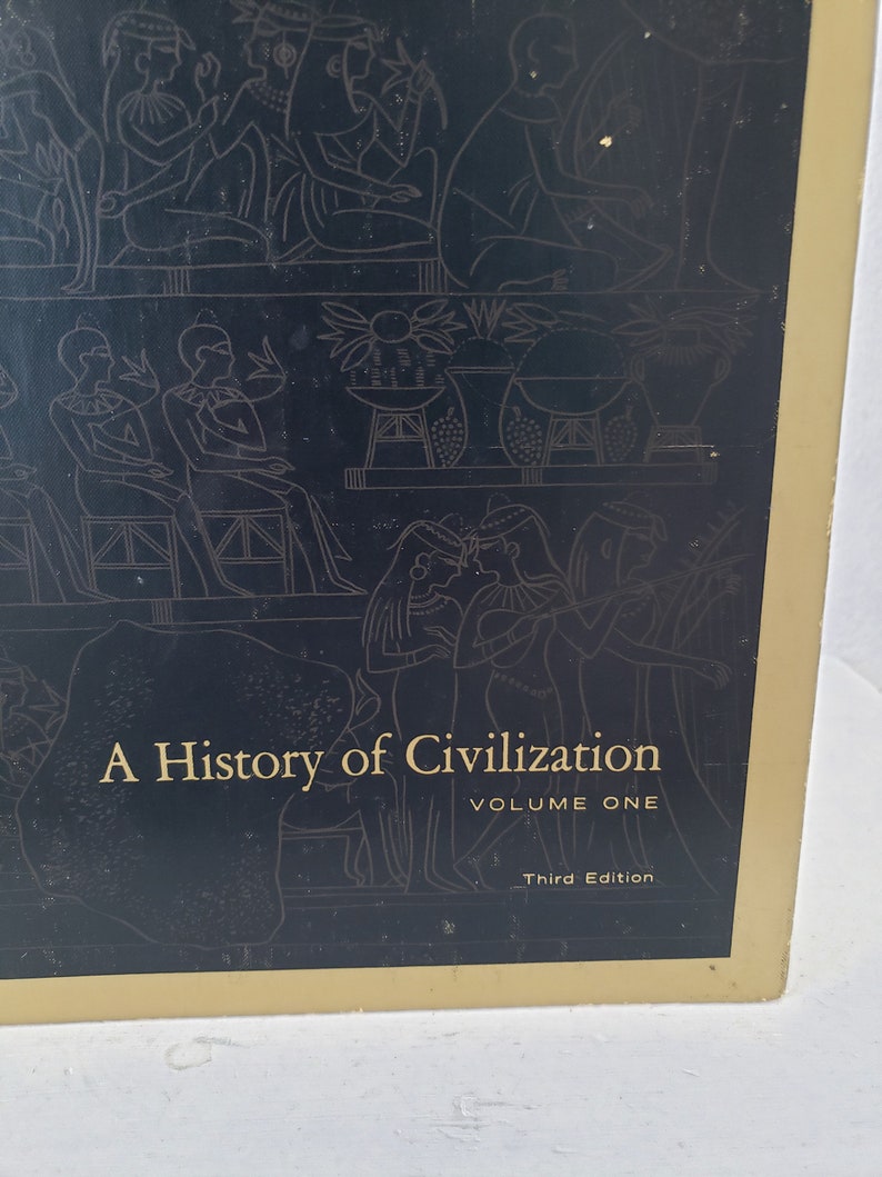 May include: A black book cover with gold lettering that reads "A History of Civilization, Volume One, Third Edition". The cover features a black and white illustration of people in ancient Egyptian clothing.