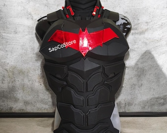 May include: A black tactical chest armor piece featuring a prominent metallic red bat-shaped emblem on the center chest. The armor displays a segmented, muscular design with textured panels and includes the white text SapCoStore on the left side.