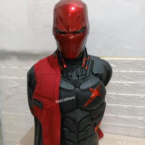 Könnte beinhalten: Eine Red Hood Cosplay-Büste mit einem metallisch roten Helm, einem schwarzen gepanzerten Brustpanzer mit rotem Stern-Emblem und einer rot-schwarzen Jacke. Der Text SapCoStore ist auf der Brust sichtbar. Die Rüstung hat detaillierte Paneele.