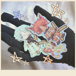 May include: A selection of colourful anime-style stickers depicting characters with fox-like features and star accents. The stickers are held in a black glove, with additional star stickers scattered around.