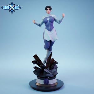 Op de afbeelding: Een beeldje van een vrouw in een paarse en lichtblauwe outfit, met een wit schortachtig detail. De figuur poseert met gebalde vuisten, staand op een gedetailleerde basis. De basis is donker met een gouden accent. Het logo "ari x el" staat in de linkerbovenhoek.