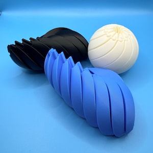 May include: A selection of 3D-printed items in different forms and hues. The items comprise a black, curved, fan-like structure, a blue, twisted, segmented shape, and a white, spherical form with a textured surface. All objects are set against a blue background.