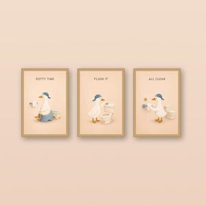 May include: A set of three framed wall art prints featuring a white duck wearing a blue cap. The first print shows the duck on a toilet with the text POTTY TIME, the second shows the duck flushing with FLUSH IT, and the third shows the duck with toilet paper and the text ALL CLEAN.