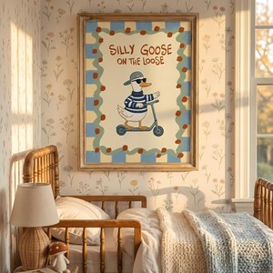 a cozy bedroom scene with a framed poster of a cartoon goose riding a scooter on the wall. The poster has a playful and whimsical design, adding a touch of fun to the room. The bed is neatly made, and there are some books and a lamp on the bedside table, creating a comfortable and inviting atmosphere.