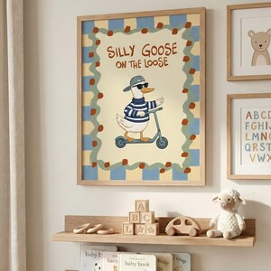 a wall with a framed poster of a cartoon goose riding a scooter, surrounded by a checkered border. Below the poster, there are two wooden shelves displaying children's books and toys, including a stuffed sheep and a wooden car.