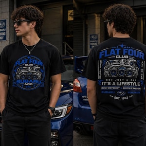 以下が含まれることがあります： 青と白のグラフィックが施された黒いTシャツ。Tシャツの前面には「FLAT FOUR CLUB SUBARU AWD」と書かれています。Tシャツの背面には「FLAT FOUR CLUB」と「NOT JUST A CAR IT'S A LIFESTYLE」というテキストが書かれています。