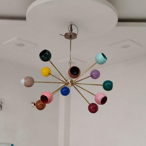 Può includere: Un lampadario moderno della metà del secolo colorato con più luci sferiche in vari colori, tra cui verde, giallo, rosa e blu. L'apparecchio ha una finitura in ottone ed è sospeso al soffitto.