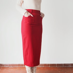 Könnte beinhalten: Ein roter Midirock mit hoher Taille und Taschen. Der Rock ist aus einem glatten, knitterarmen Stoff.