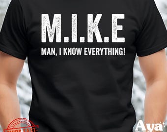 May include: Black t-shirt with the text "M.I.K.E. MAN, I KNOW EVERYTHING!" in white, distressed lettering. The shirt is a crew neck style and appears to be made of a soft material. The shirt is a casual wear item.