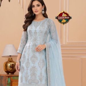 May include: A light blue embroidered salwar kameez suit with matching pants and a sheer dupatta. The suit features intricate silver embroidery and is suitable for special occasions. The logo "SAREESUTRAIN" is visible.