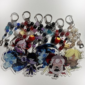 Pode incluir: Uma coleção de chaveiros com designs de personagens de desenhos animados. Cada chaveiro tem um fecho prateado e uma corrente de contas com várias contas, berloques e dados. Os designs dos personagens são coloridos e detalhados, com uma variedade de poses e expressões.