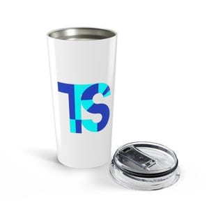 May include: A white stainless steel tumbler with a metallic rim and a clear plastic lid. The side of the tumbler features a large, stylized graphic of the letters TS, composed of overlapping geometric squares in shades of blue and cyan.