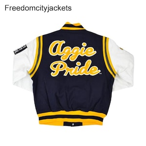 May include: A navy blue and white varsity jacket with yellow accents. The back of the jacket features the words "Aggie Pride" in yellow script. The jacket has white sleeves and a yellow and black striped collar and cuffs.
