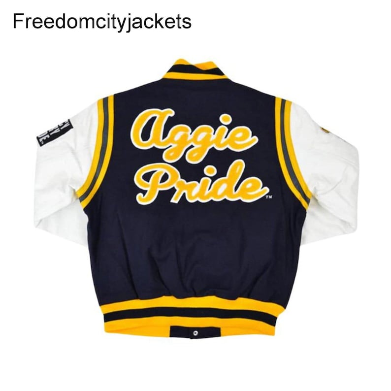 May include: A navy blue and white varsity jacket with yellow accents. The back of the jacket features the words "Aggie Pride" in yellow script. The jacket has white sleeves and a yellow and black striped collar and cuffs.