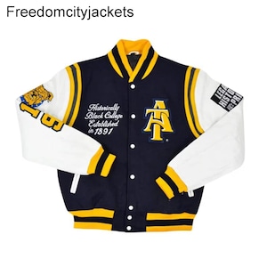 Könnte beinhalten: Marineblaue und weiße Collegejacke mit gelben Akzenten. Die Jacke trägt den Text "Historically Black College Established in 1891" und ein gelbes "AT"-Logo. Die Ärmel sind weiß mit gelben Streifen.