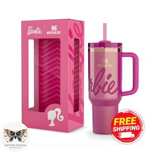May include: A pink Stanley tumbler with a handle and straw, featuring the Barbie logo. The tumbler is displayed next to its pink box, which also has the Barbie logo and a silhouette. The box has a window showing a pink zig-zag pattern.