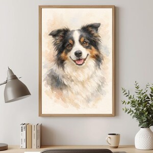 May include: A framed watercolor painting of a dog, featuring a smiling face with black, white, and brown fur. The artwork is set against a soft, neutral background, and the frame is a light brown color. The painting is displayed on a wall.
