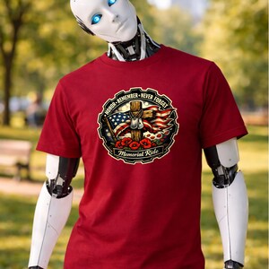 May include: A maroon t-shirt featuring a circular graphic with the text "HONOR - REMEMBER - NEVER FORGET" and "Memorial Ride". The graphic includes a cross, American flag, dog tags, and poppies.