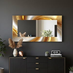 Könnte beinhalten: Rechteckiger Wandspiegel mit einem gold-weißen abstrakten Designrand. Der Spiegel wird über einem schwarzen Schrank mit goldfarbener Hardware ausgestellt. Eine Digitaluhr zeigt die Uhrzeit an.