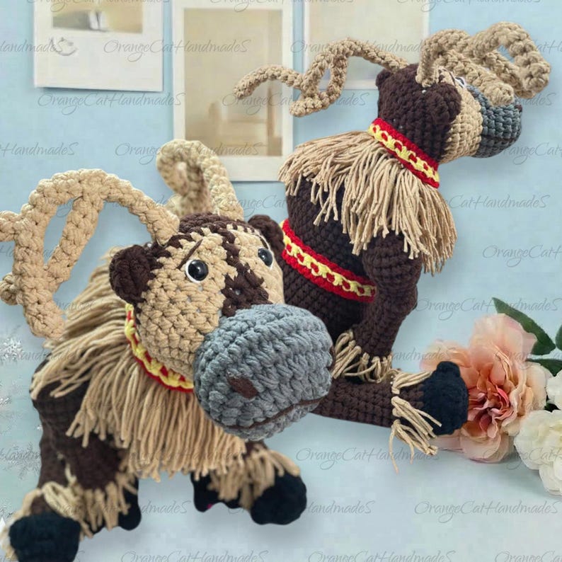 May include: Two crocheted reindeer figures featuring dark brown bodies, tan antlers, and grey muzzles. Each reindeer has a tan fringe mane, black hooves, and a decorative collar with red and yellow patterns. The figures are crafted with yarn.