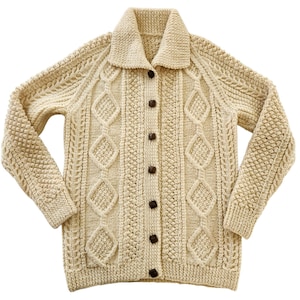 May include: Cream-coloured, button-down cardigan with a shawl collar. The knitted sweater features diamond and textured patterns, with brown buttons. A classic, cosy long-sleeved garment.