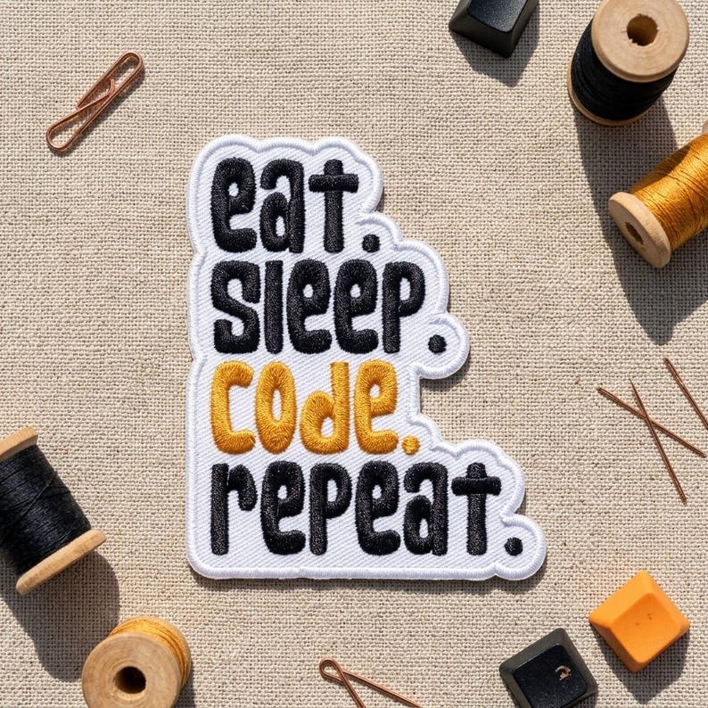 May include: A white embroidered patch with a black border featuring the text "eat. sleep. code. repeat." in a bold, rounded font. The words "eat.", "sleep.", and "repeat." are stitched in black, while the word "code." is stitched in gold.