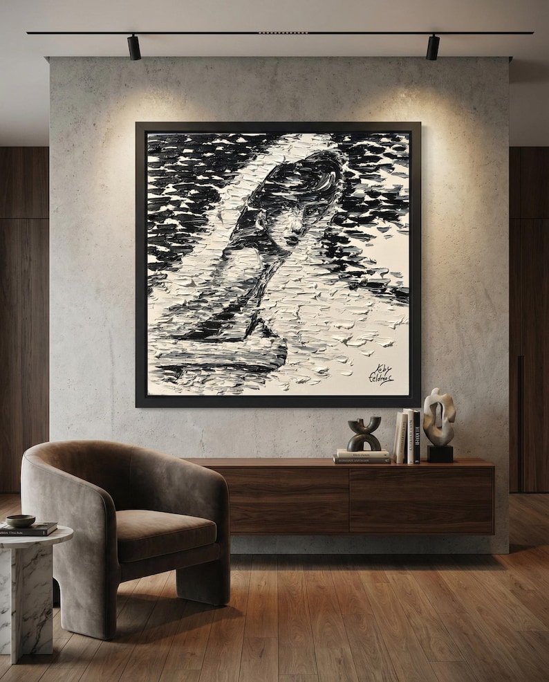 Puede incluir: Una gran pintura abstracta en blanco y negro enmarcada de la cara y la parte superior del cuerpo de una mujer. La obra de arte se exhibe sobre un mueble de madera oscura y un sill&oacute;n curvo marr&oacute;n. La habitaci&oacute;n tiene un dise&ntilde;o moderno y minimalista.