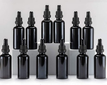 May include: A set of 12 black glass dropper bottles with black caps. The bottles are arranged in a pyramid shape on a white surface.