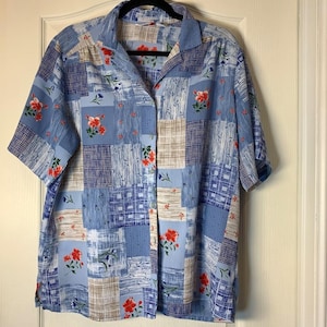 Peut inclure: Chemise boutonnée à manches courtes avec un motif patchwork. La chemise présente une base bleu clair avec des carrés de motifs et de couleurs variés, dont blanc, beige et bleu foncé. Des accents floraux rouges sont dispersés dans le motif.
