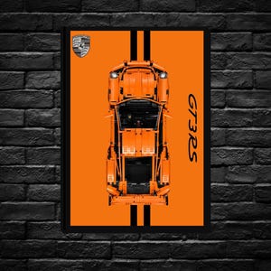 Peut inclure: Impression d'art d'une voiture GT3RS orange avec des rayures noires et le logo Porsche. La voiture est vue de dessus, avec le texte "GT3RS" en noir sur le côté droit. L'impression est encadrée en noir.
