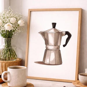 May include: A framed print of a silver stovetop espresso maker with a black handle and top. The artwork is set against a white background, framed in light wood. A cup of coffee and a bouquet of white flowers are in the foreground.
