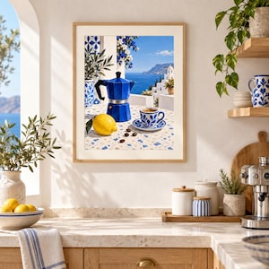 Puede incluir: Una lámina de arte mural enmarcada que muestra una cafetera italiana azul, una taza de espresso a juego con motivos azules y blancos sobre un platillo, un limón amarillo y granos de café sobre una mesa de terrazo frente al mar.