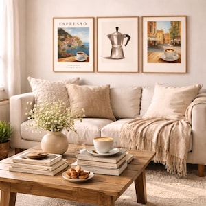 May include: A cozy living room scene featuring a light-colored sofa with throw pillows and a fringed blanket. Three framed art prints depict coffee-themed images. A wooden coffee table displays books, a vase of flowers, and a cup of coffee.