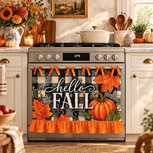 Peut inclure: Un cache-poignée de four en tissu avec un motif à carreaux noir et blanc, des feuilles d'érable orange, une grosse citrouille orange et le texte hello FALL en blanc. Il comporte des nœuds orange et un volant orange sur le bas.