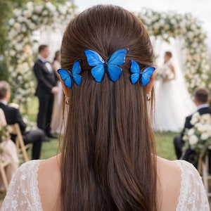 May include: A woman's brown hair is adorned with three bright blue butterfly hair clips. The butterflies are positioned across the back of the head, adding a whimsical touch. The background shows a wedding ceremony.